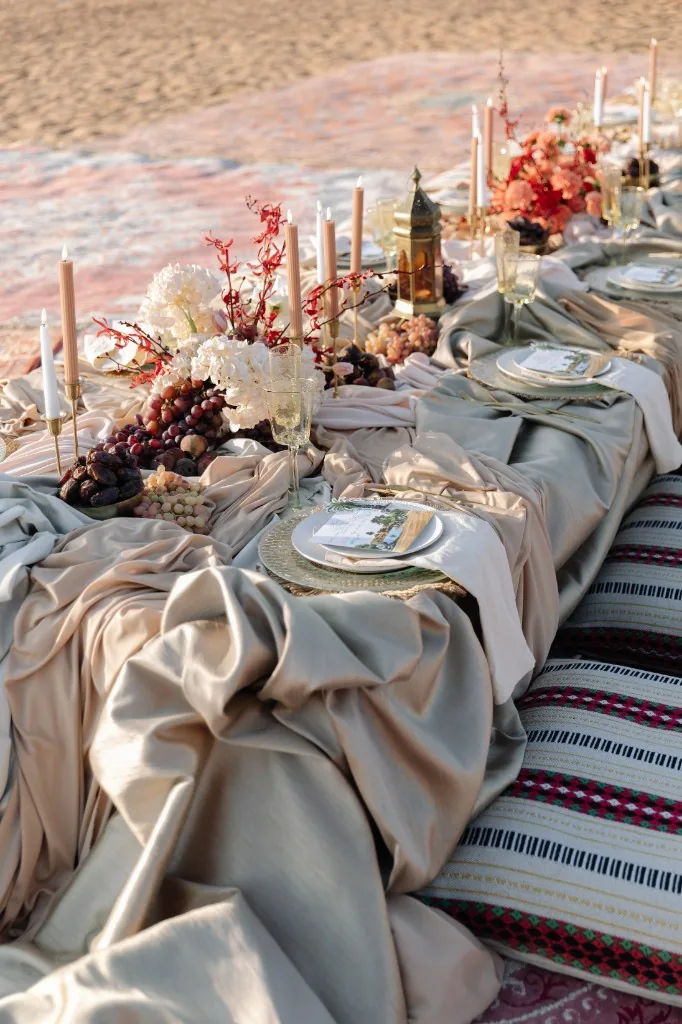 Overhead view of a desert wedding table with layered linens, florals and candlelight