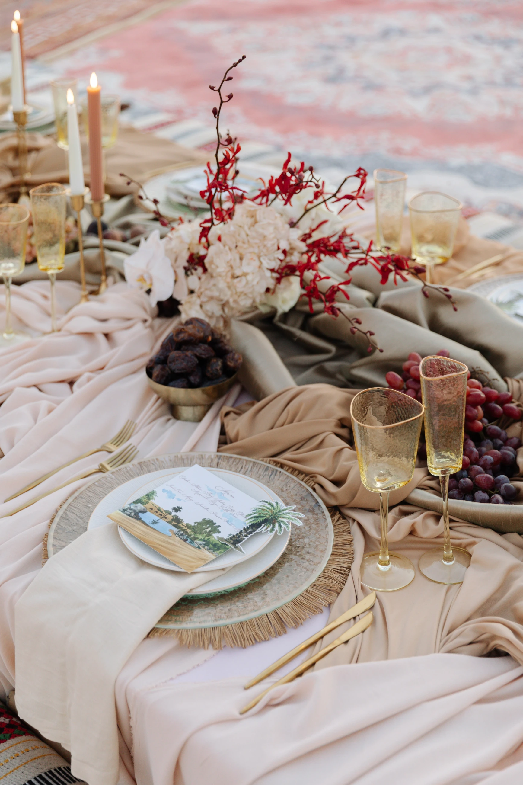 Al Maha desert editorial tablescape: blush and red florals, candlelight and layered stationery on a styled wedding table