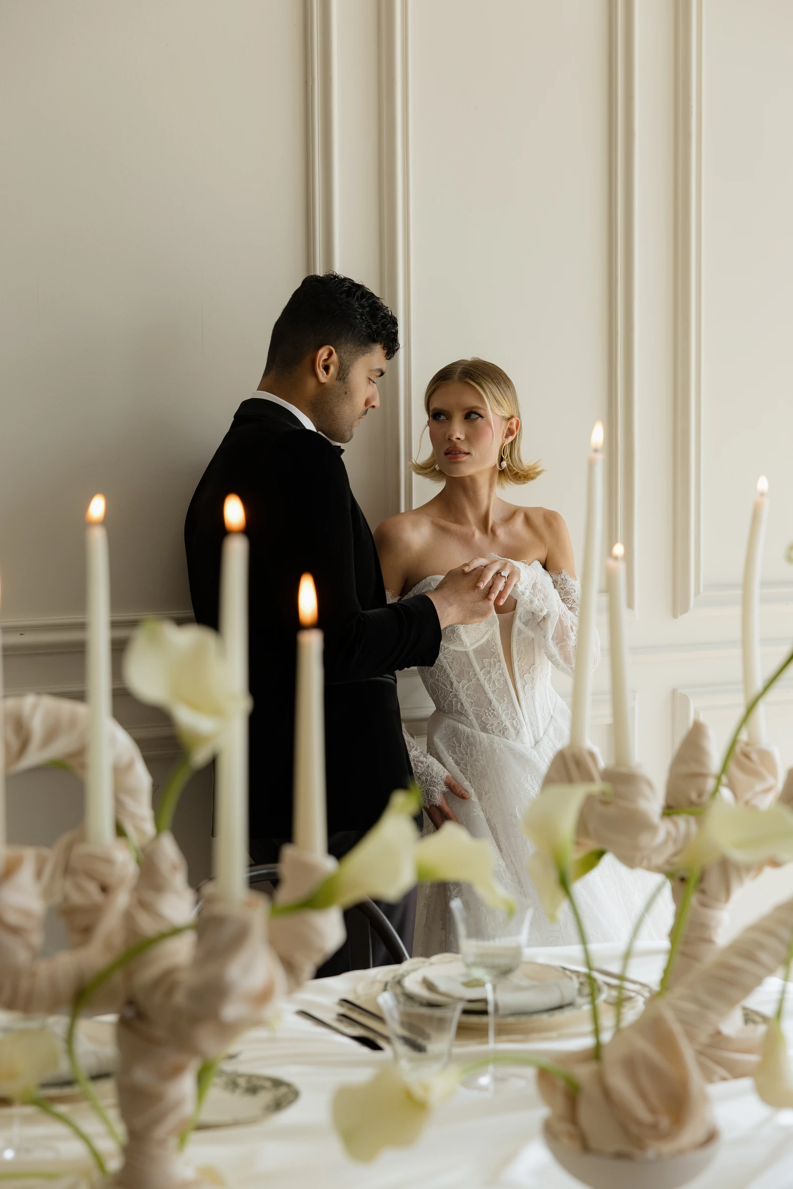 Bride and groom in an elegant candlelit interior with taper candles and soft florals